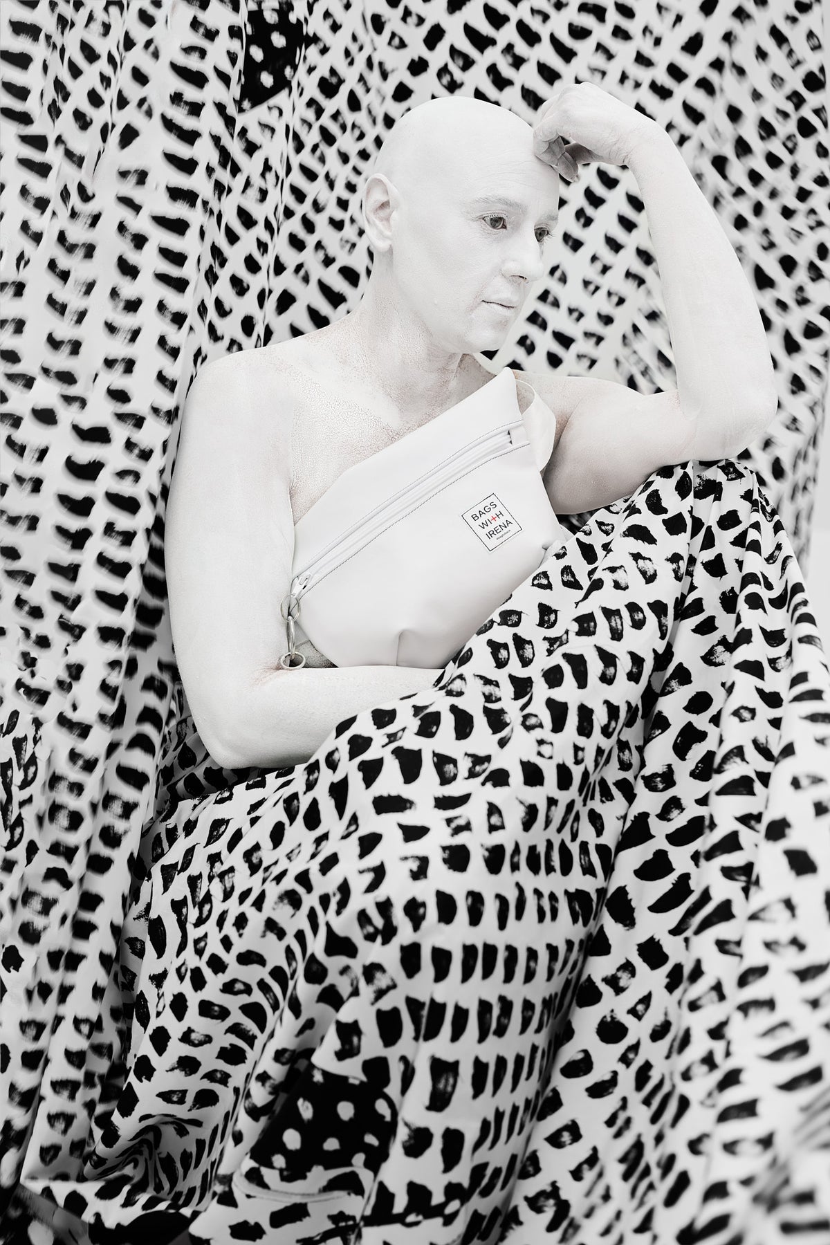 Irena Pejčić reclining on black and white fabric, the white bag across her chest