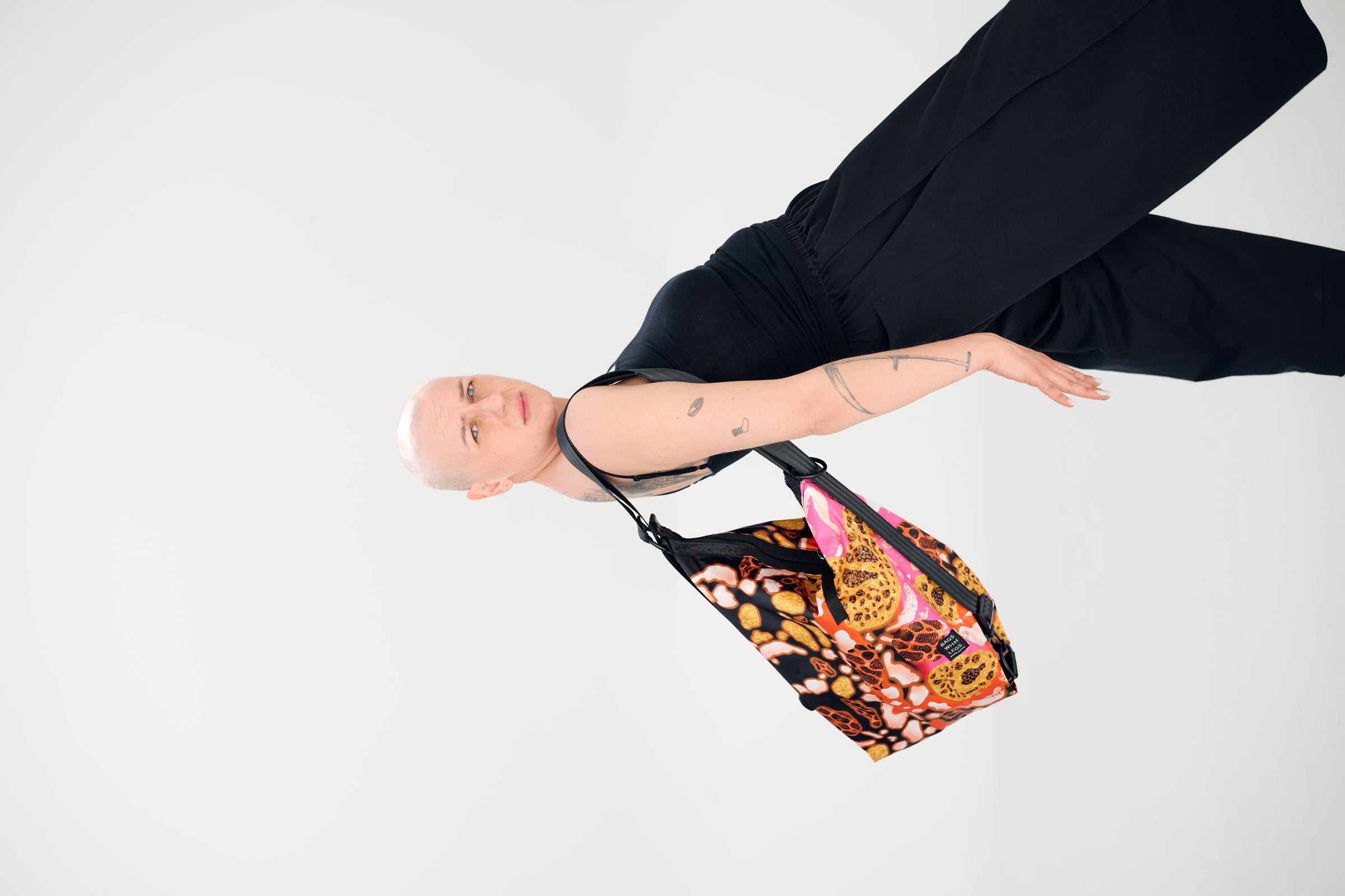 Eine scheinbar schwebende Person trägt eine bunte Tasche von Bags With Legs
