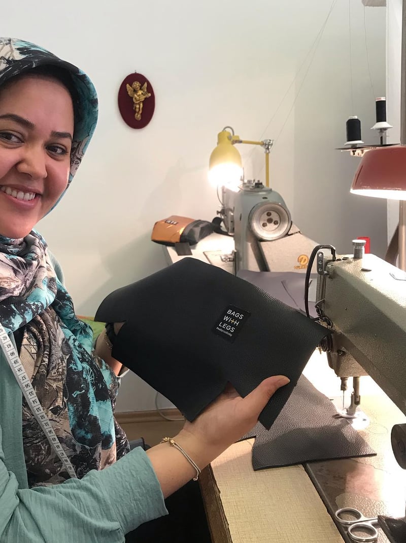 Asal Huseini hält eine fertige schwarze Tasche an ihrer Nähmaschine