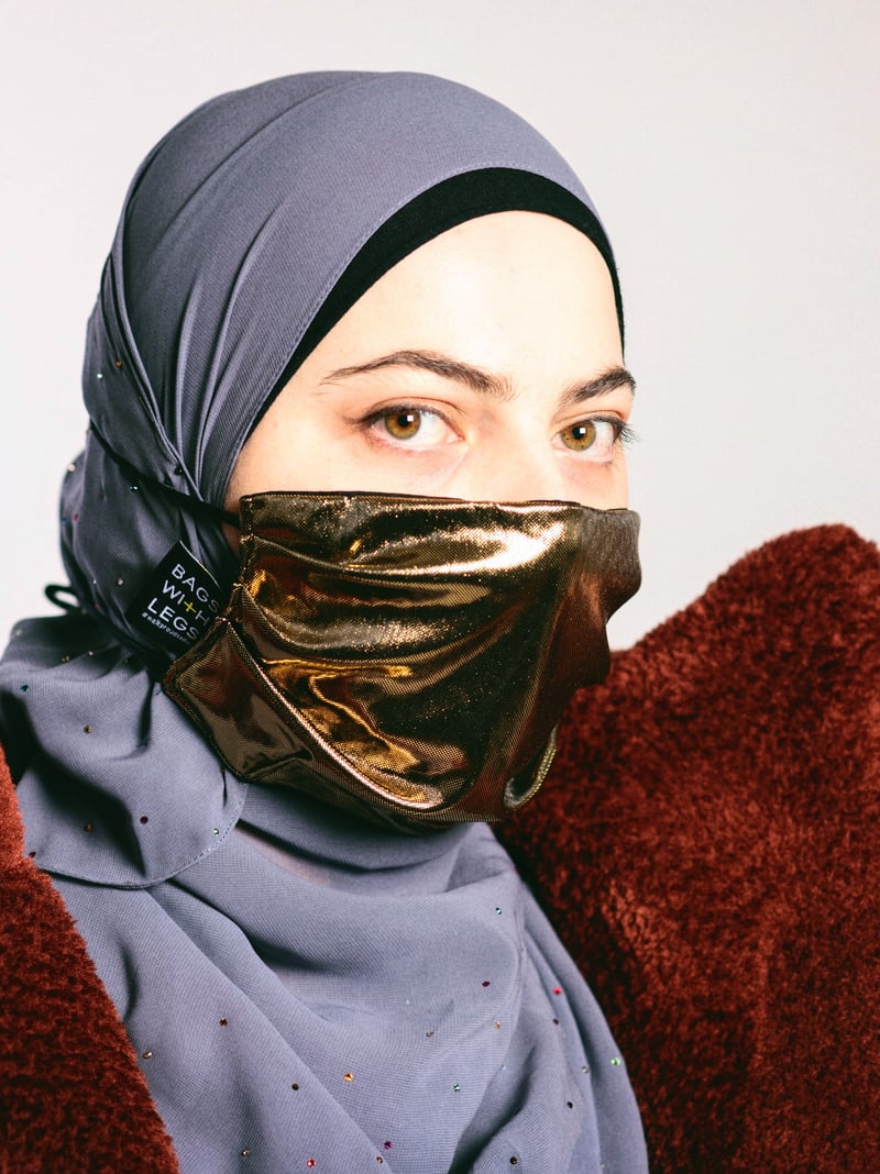 Laura Kadiewa im Porträt, mit grauem Kopftuch und goldener Gesichtsbedeckung