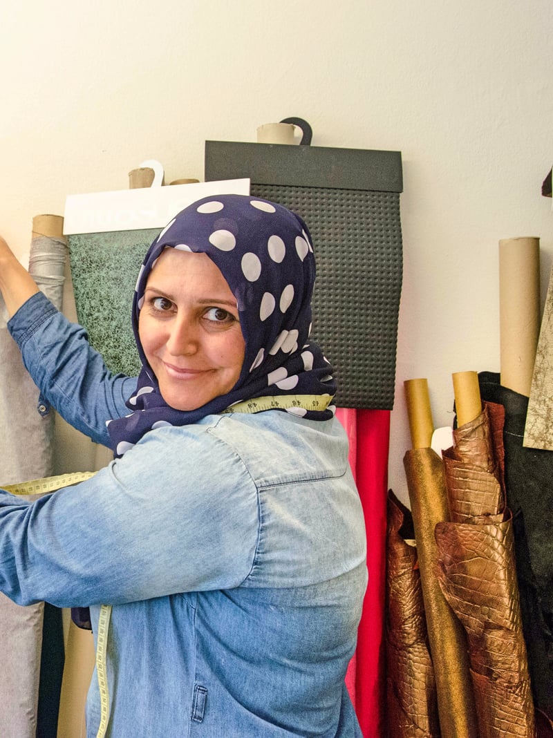 Sumaya Shaker mit verschränkten Armen im Atelier, dahinter Lederrollen