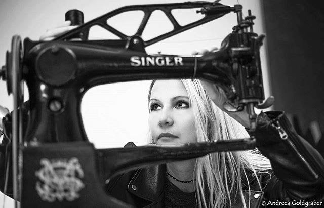 Eine Frau, gerahmt vom Arm einer antiken Singer-Nähmaschine, in Schwarzweiß